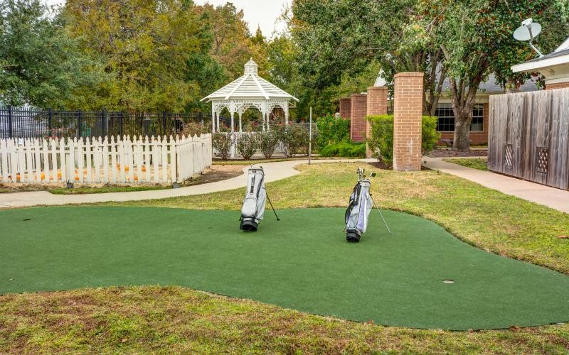 a putting green with a gazeebo in the back