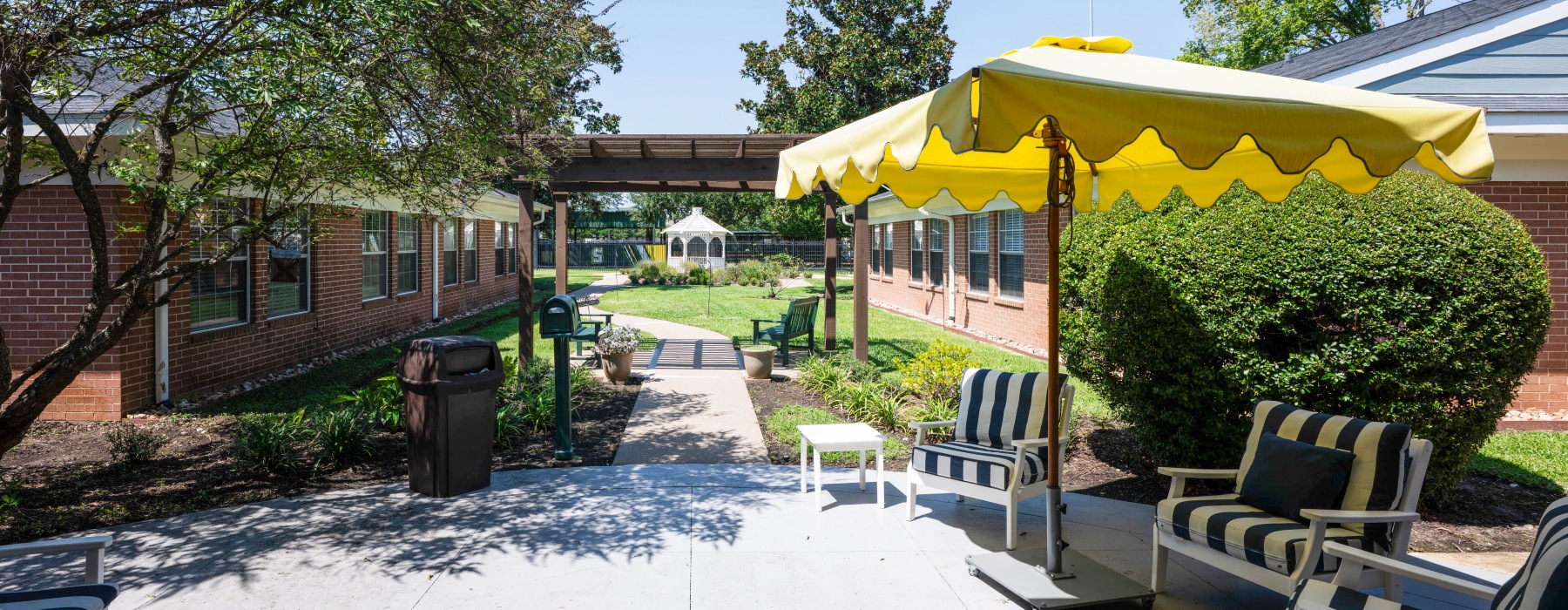 a sunny patio and garden with a gazebo in the background